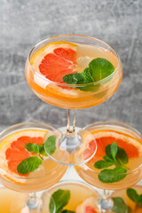 Tower made of glasses with grapefruit cocktail on grey background, closeup