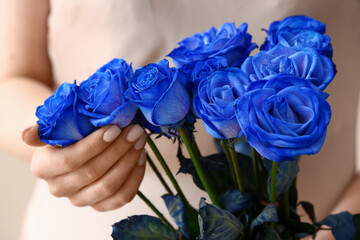 Woman with beautiful blue roses on light background, closeup