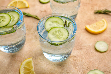 Glass with cucumber lemonade on color background