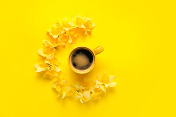 Cup of coffee and beautiful daffodils on color background