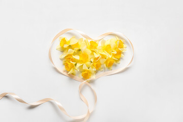 Ribbon and beautiful daffodils on light background