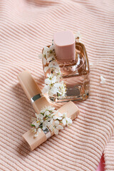 Beautiful blooming branches, sweater and cosmetics on color background, closeup