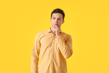Thoughtful young man on yellow background