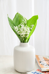 Vase with beautiful lily-of-the-valley flowers on light background
