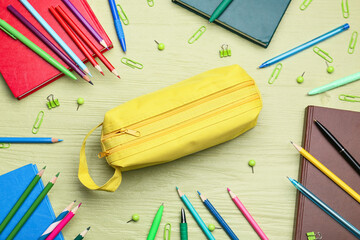 Pencil case and stationery on color wooden background