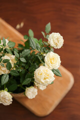 Beautiful white roses in pot on wooden background