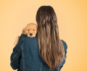 Back view woman with long hair snuggling sleeping golden retriever puppy dog