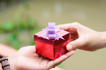 hand of man holds a red gift box to hand woman. he is preparing to give her lover.