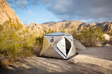 A view of a rocky desert landscape, featuring a heat controlled tent shelter. - Powered by Adobe