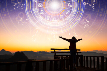 Woman raising hands looking at the sky. Astrological wheel projection, choose a zodiac sign. Trust horoscope future predictions, consulting stars. Power of universe, astrology esoteric concept. - obrazy, fototapety, plakaty