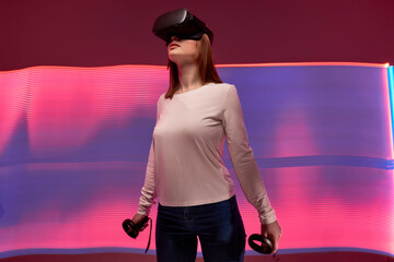 Young woman getting experience using VR-headset glasses of virtual reality in studio, looking away,...