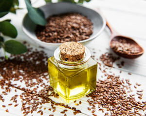 Flax seeds or linseeds in spoon and bowl with glass of linseed oil