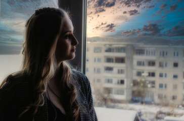 Fototapeta na wymiar young woman looks out the window, apathy