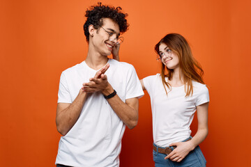 young couple in white t-shirts and glasses fun fashion orange background