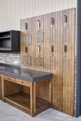 Different barbecue grids hang on wainscoting made of thin planks and elegant furniture set in summer kitchen on open terrace