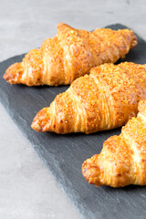 three tasty croissants on black stone background. French food. Close up. Low key