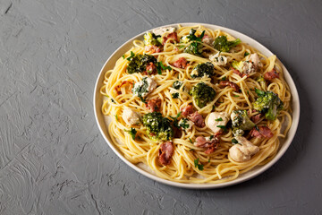 Homemade Chicken Bacon Broccoli Alfredo on a gray background, low angle view. Copy space.