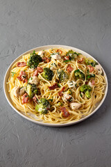 Homemade Chicken Bacon Broccoli Alfredo on a plate on a gray surface, side view.