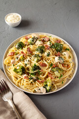 Homemade Chicken Bacon Broccoli Alfredo on a plate on a gray background, side view.