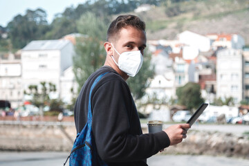 tourist man with mask walking through the town with his digital tablet and his coffee in the new...
