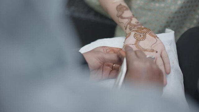 Close up shot of woman applying mehndi in traditional Indian marriage