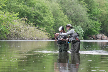 fishing guide with a young woman fly fishing for trout in a clear river