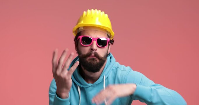 casual man dancing like a rapper, gesturing then taking off his sunglasses and helmet and fooling around