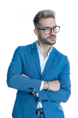 confident bearded man in suit crossing arms and looking to side