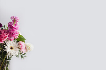 Pink and pastel white flowers in Modern glass vase on gray wall background with copyspace