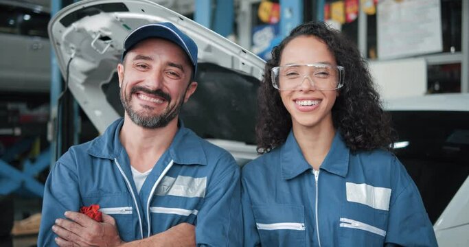 Two smiling car mechanic standing look at camera in garage, Portrait of technician in uniform in front of automobile. Repairing car team service concept