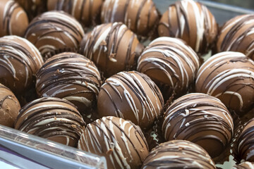 A view of several chocolate truffle balls, drizzled with chocolate and vanilla streaks.