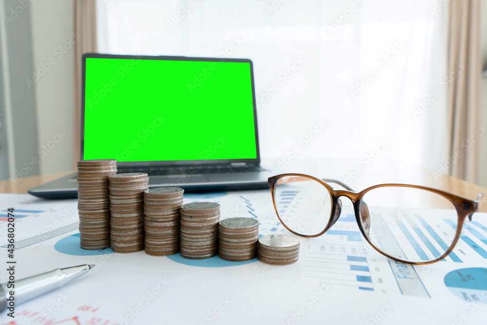 Poster business documents on table with laptop computer and coin stacks and graph financial diagram. laptop