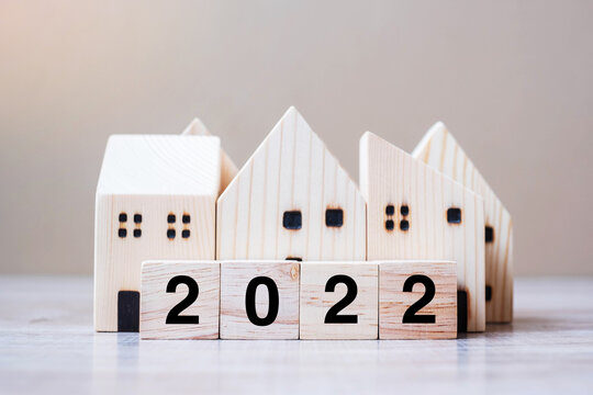 2022 Happy New Year with house model on table wooden background. Banking, real estate, investment, financial, savings and New Year Resolution concepts