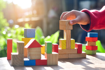 Happy cute little child boy play with wooden blocks construction on the table at home. Learning...