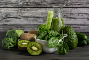 Fresh organic green smoothie with spinach, cucumber, kiwi, celery, and avocado on wooden...