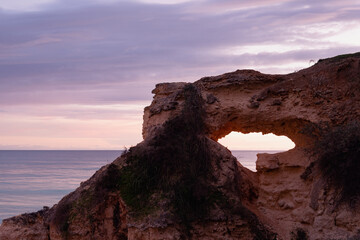 Ocean sunset view through hole in the cliffs along the cost of Armacao de Pera in the Algarve in Porgugal.