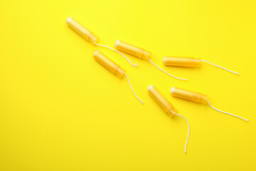 Orange tampons on yellow background, space for text