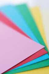 Fototapeta premium Colorful paper sheets shaped as a fan. Vertical photo. Copy space. Sharp and blurred areas.