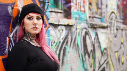 Fototapeta na wymiar young urban woman leaning against grafitti wall