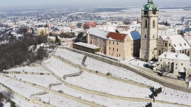 Vineyard terraces under snow next to a small town church clocktower.