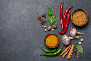 Various spices on black background. Culinary or menu background. Chili peppers, herbs, mustard seeds, curry, cinnamon, cardamom, garlic, cloves, nutmeg, star anise