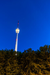 Germany, TV tower building of stuttgart city illuminated by night with blue sky surrounded by trees, forest and nature in the urban area