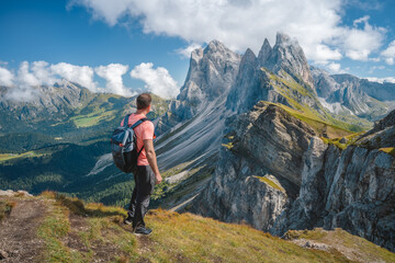 Fototapeta premium A man with backpack enjoy landscape of Seceda peak in Dolomites Alps, Odle mountain range, South Tyrol, Italy, Europe. Travel vacation concept