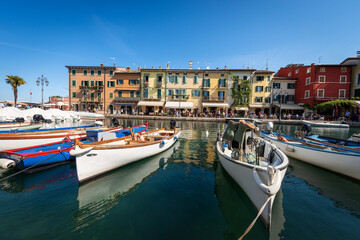Fototapeta na wymiar Small Port of the Lazise village with fishing boats, tourist resort on the coast of Lake Garda (Lago di Garda). Verona province, Veneto, Italy, southern Europe.