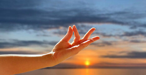 yoga, gesture and healthy lifestyle concept - hand of meditating yogi woman showing gyan mudra over...