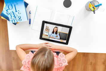 online education, e-learning and technology concept - happy student girl with teacher on tablet computer screen having video class at home