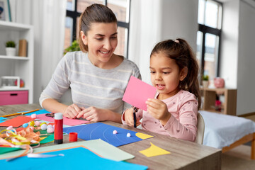 family, art and craft concept - mother spending time with her little daughter with glue making...