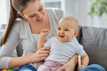 family, motherhood and people concept - happy smiling mother and little baby playing with rattle at home