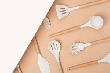 Cooking utensil set. Silicone kitchen tools with wooden handle on beige background with copy space....