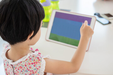 Little asian girl playing digital tablet at home